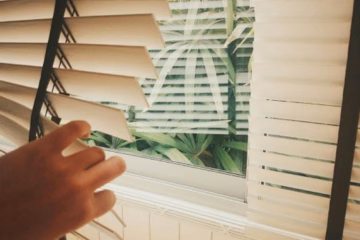 person holding white window blinds